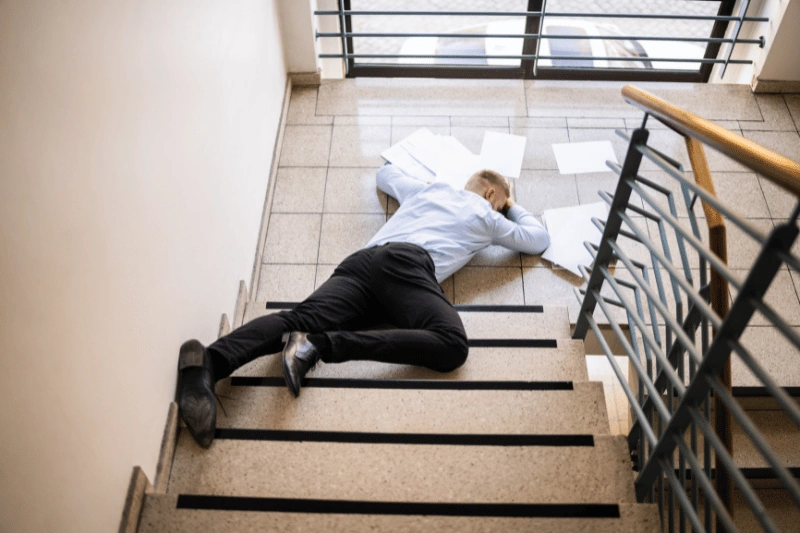 Man lying face down on a staircase landing with scattered papers around him illustrating the significance of Slip and Fall Attorney in Myrtle Beach